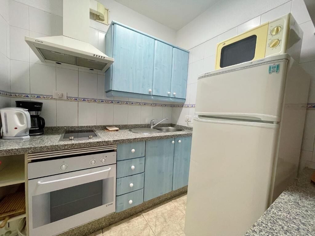 Una cocina con horno empotrado, microondas, fregadero y armarios.