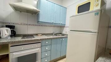Una cocina con horno empotrado, microondas, fregadero y armarios.