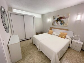 Un dormitorio con dos camas, una mesita de noche, un armario y un cuadro en la pared.