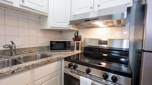 A modern kitchen with white cabinets, a stainless steel range, a microwave, and a granite countertop. - 2BR Ground Floor, Sleeps 8, Pets ok - SPI (South Padre Island)