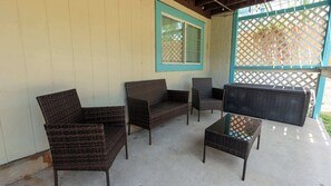 Ein möblierter Außenbereich mit Korbmöbeln, darunter eine Couch, Stühle und ein Couchtisch.