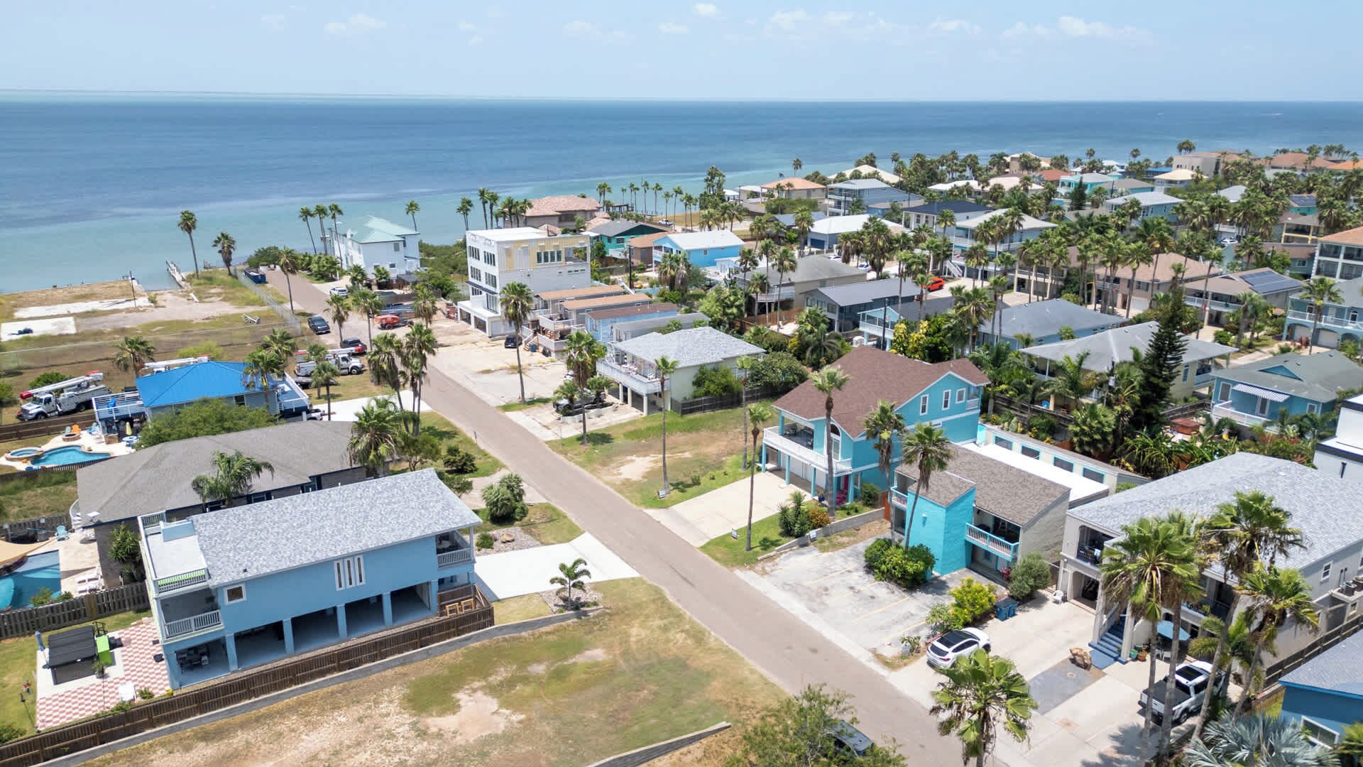 A coastal residential area with houses, a clear view of the ocean, and a swimming pool.
