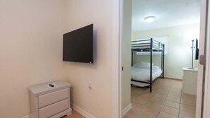 Ein Zimmer mit einem Etagenbett, einem Nachttisch mit Fernbedienung und einem an der Wand befestigten Fernseher.