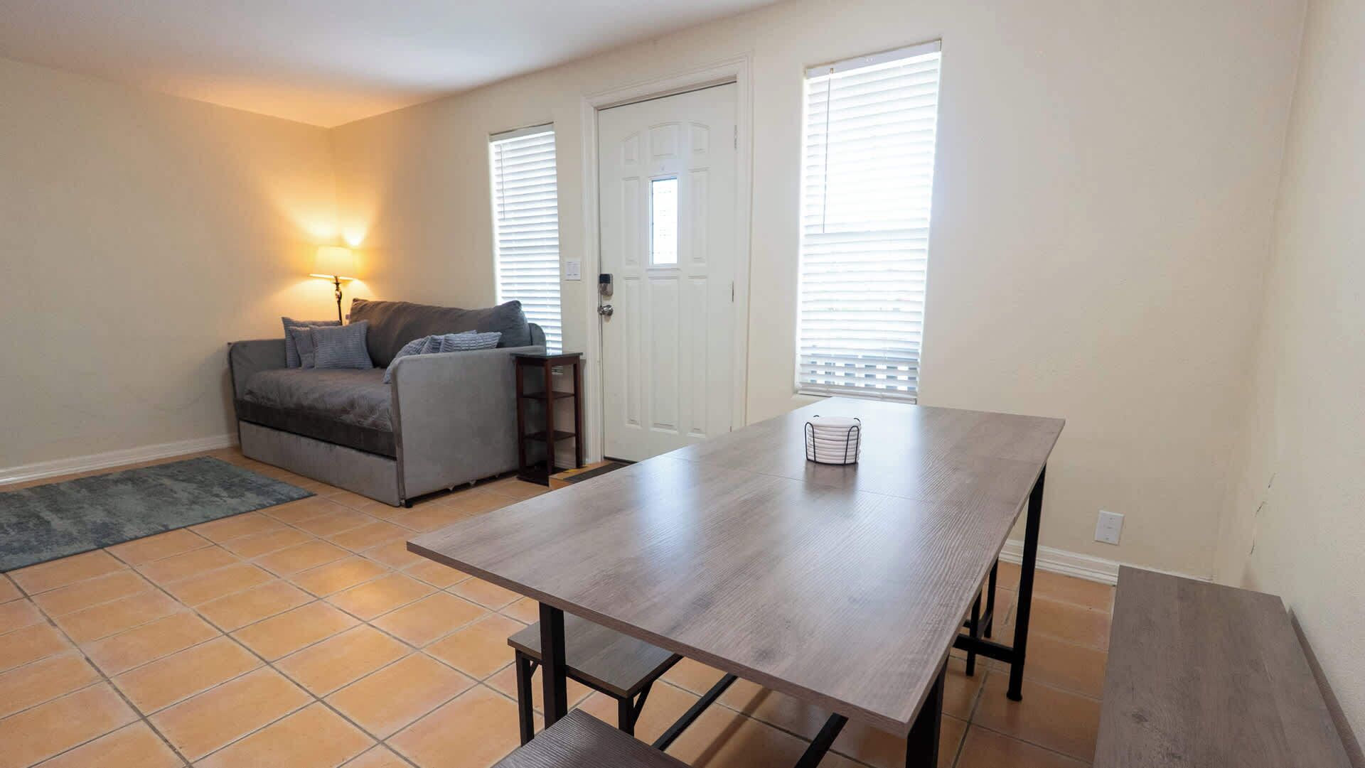 Una sala de estar con un sofá, una mesa de comedor y una lámpara.