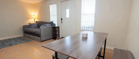 Una sala de estar con un sofá, una mesa de comedor y una lámpara.