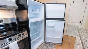 Eine Küche mit einem Herd, einem Backofen und zwei offenen Kühlschränken.
