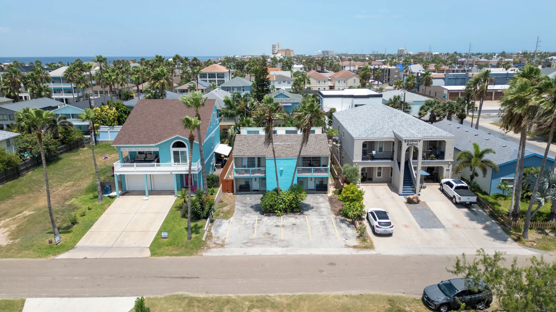 A residential area with houses, a swimming pool, and a view of the ocean.