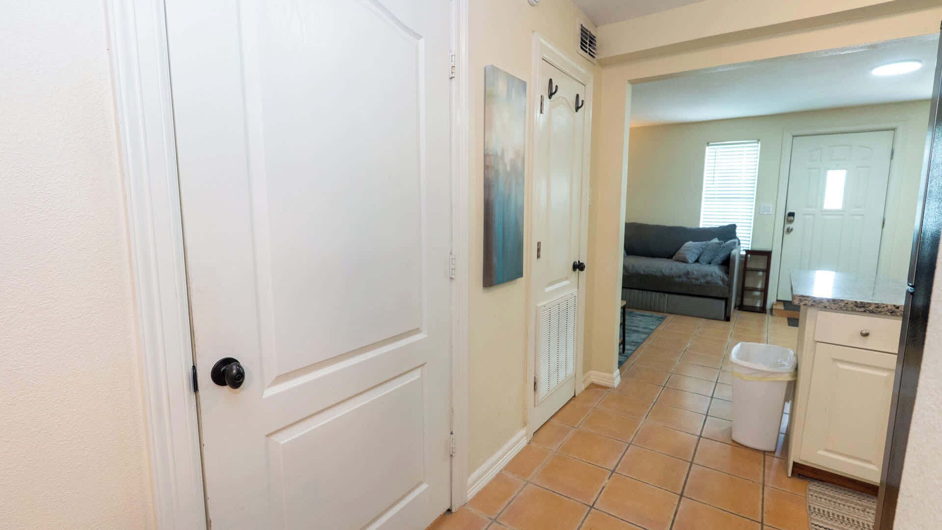 A hallway leading to a living area with a sofa and a window.