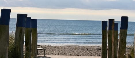 A wooden pathway leading to a beach with a metal railing.
