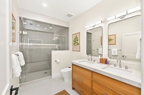Ein modernes Badezimmer mit Duschkabine aus Glas, Toilette, Waschtisch mit Spiegel und Waschbecken.