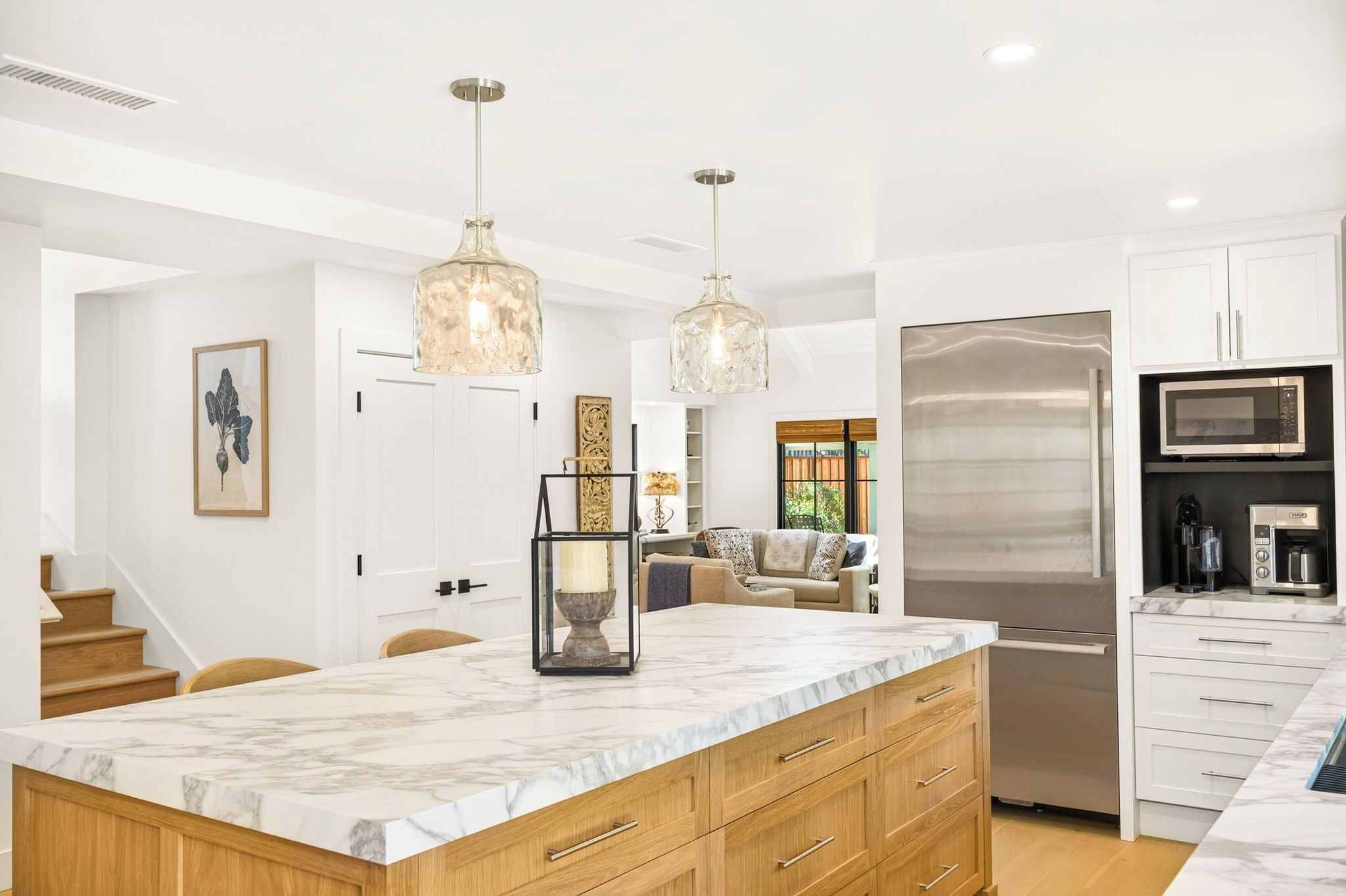 A modern kitchen with marble countertops, stainless steel appliances, and pendant lighting.