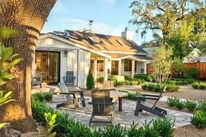 Ein Haus mit überdachter Terrasse, Sitzgelegenheiten im Freien und einem gepflegten Garten.