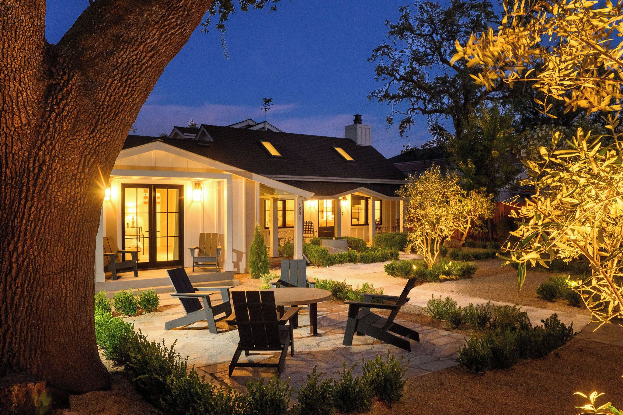 A house with a patio area featuring outdoor furniture and a well-lit entrance.
