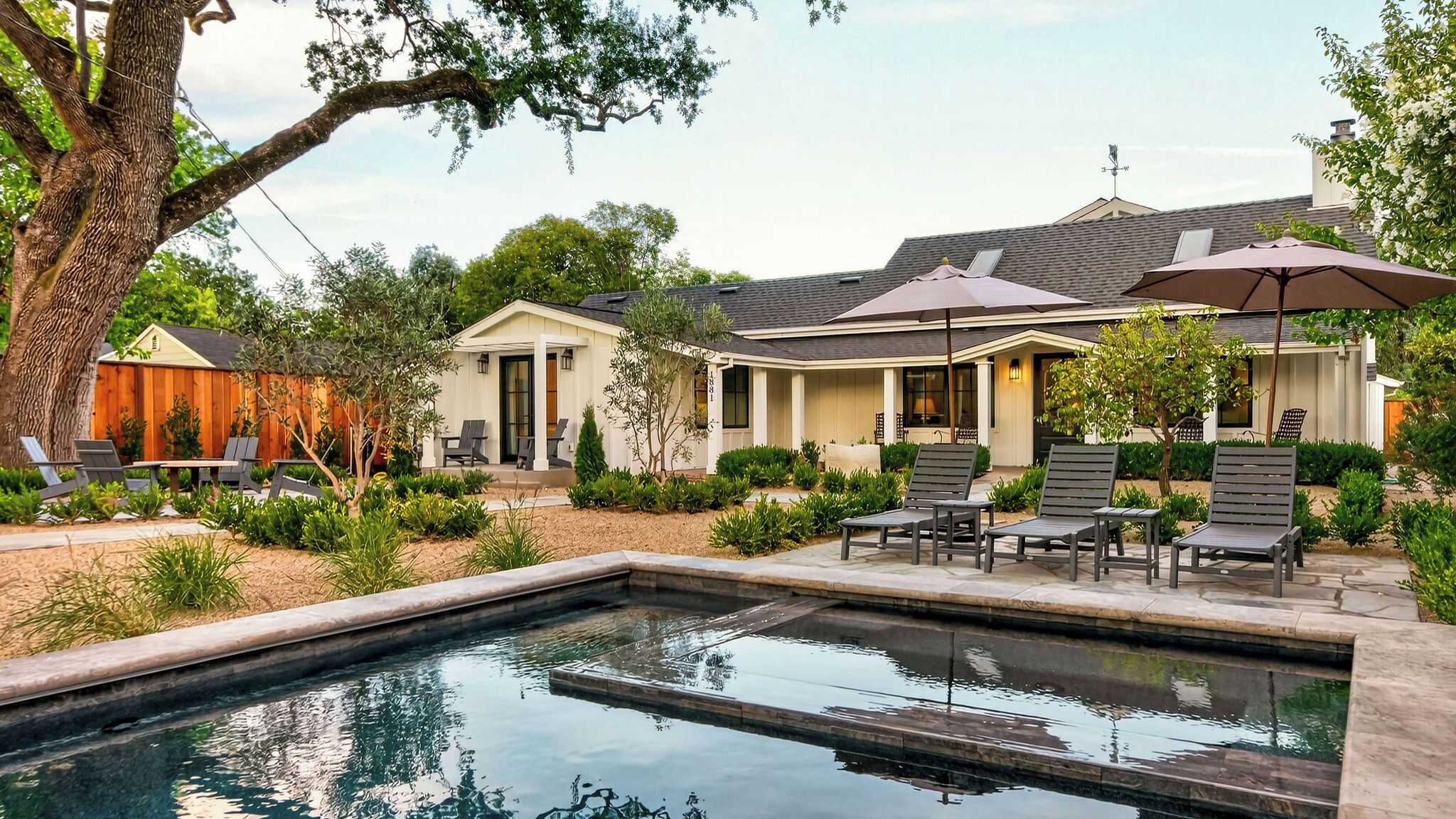 A residential property with a swimming pool, outdoor seating, and a covered patio area.