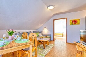 Ein gemütliches Wohnzimmer mit Essbereich, einer Couch, einem Fernseher und einem Bild an der Wand.