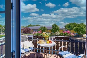 A balcony with a table, chairs, and a view of a building and trees. - Holiday apartment with 1 bedroom (Prerow)