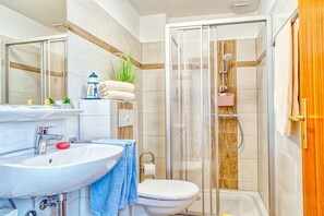 A bathroom with a glass-enclosed shower, a sink, and a toilet. - Holiday apartment with 1 bedroom (Prerow)