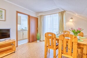A dining area with a wooden table, chairs, and a television on a stand. - Holiday apartment with 1 bedroom (Prerow)