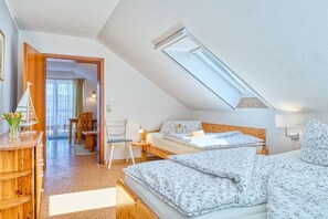 A bedroom with two beds, a wooden desk, a chair, and a skylight. - Holiday apartment with 1 bedroom (Prerow)
