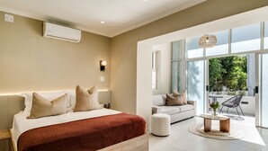 Un dormitorio moderno con una cama grande, un sofá y una zona de comedor con vistas a zonas verdes.