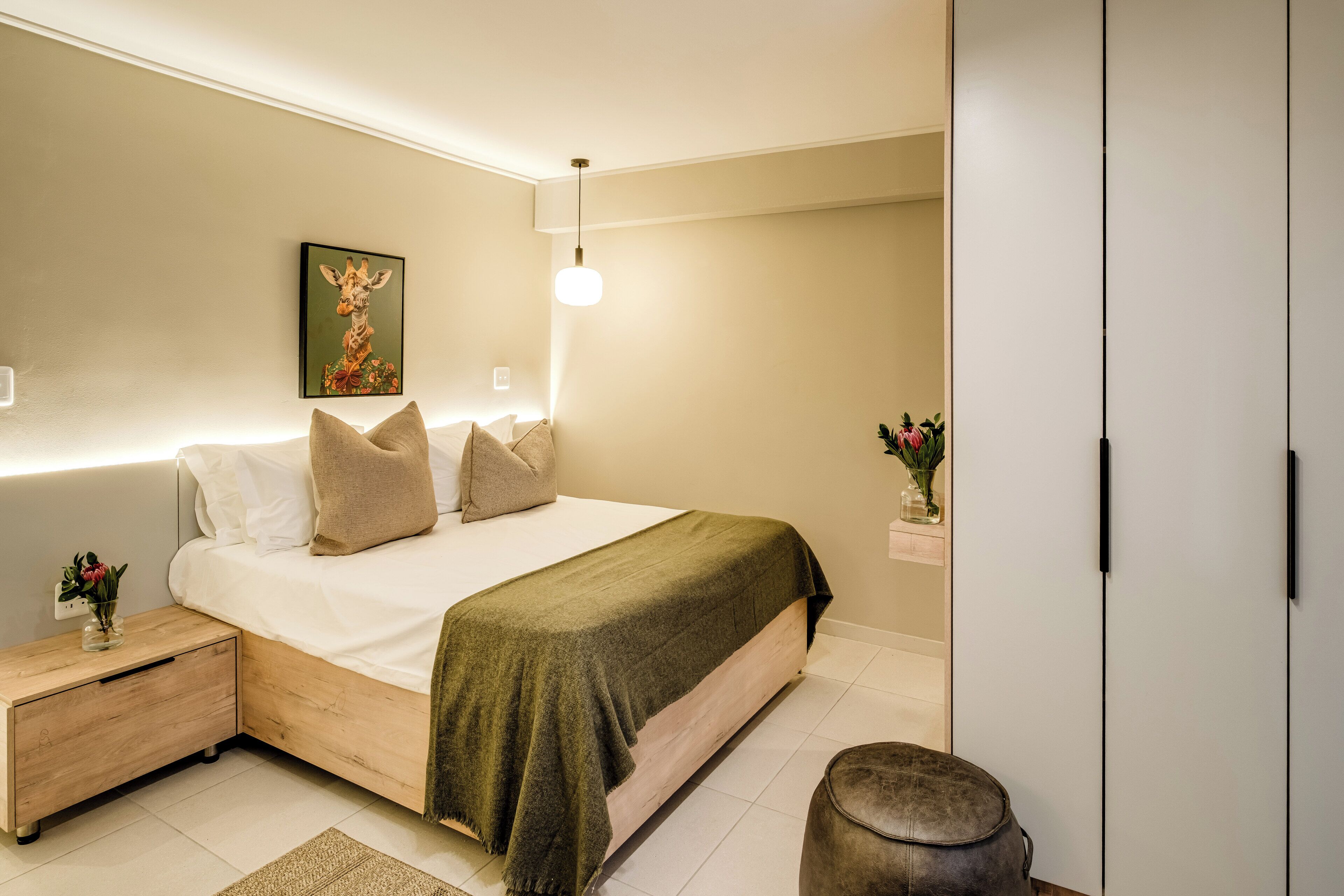 A bedroom with a bed, bedside tables, a nightstand, a lamp, and a wardrobe.