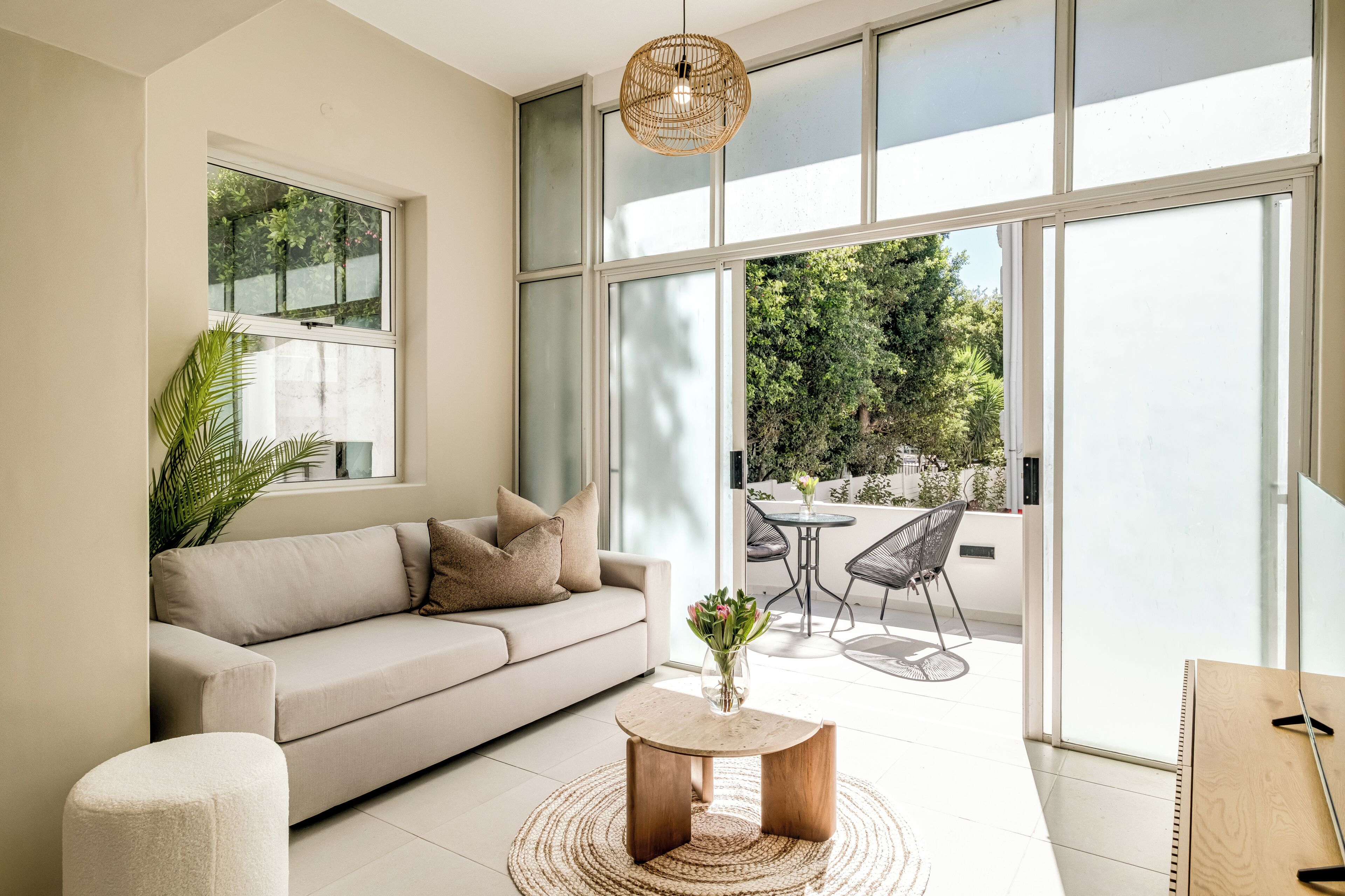 A modern living room with a sofa, a coffee table, and a dining area with chairs.