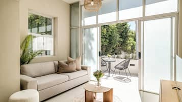 A modern living room with a sofa, a coffee table, and a dining area with chairs.