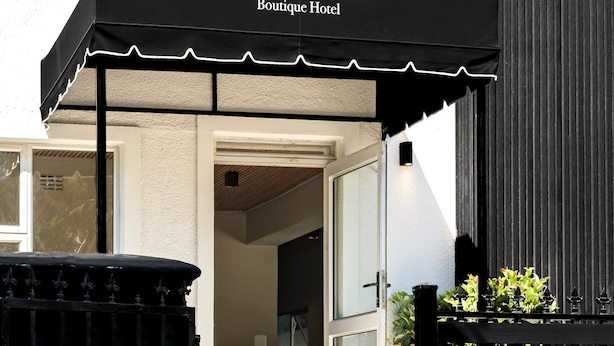 Entrada de un hotel con un toldo negro que muestra el nombre 'The Guest Boutique Hotel'.