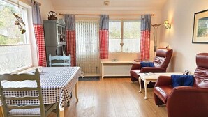Un salon chaleureux avec une table à manger, des chaises, un canapé et un meuble.