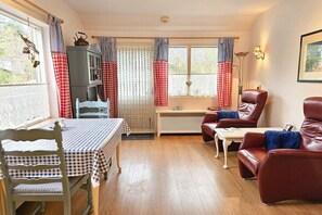 Una sala de estar acogedora con una mesa de comedor, sillas, un sofá y un aparador.