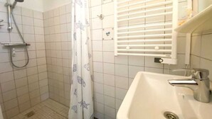 Une salle de bain avec une douche, un lavabo et un porte-serviettes.