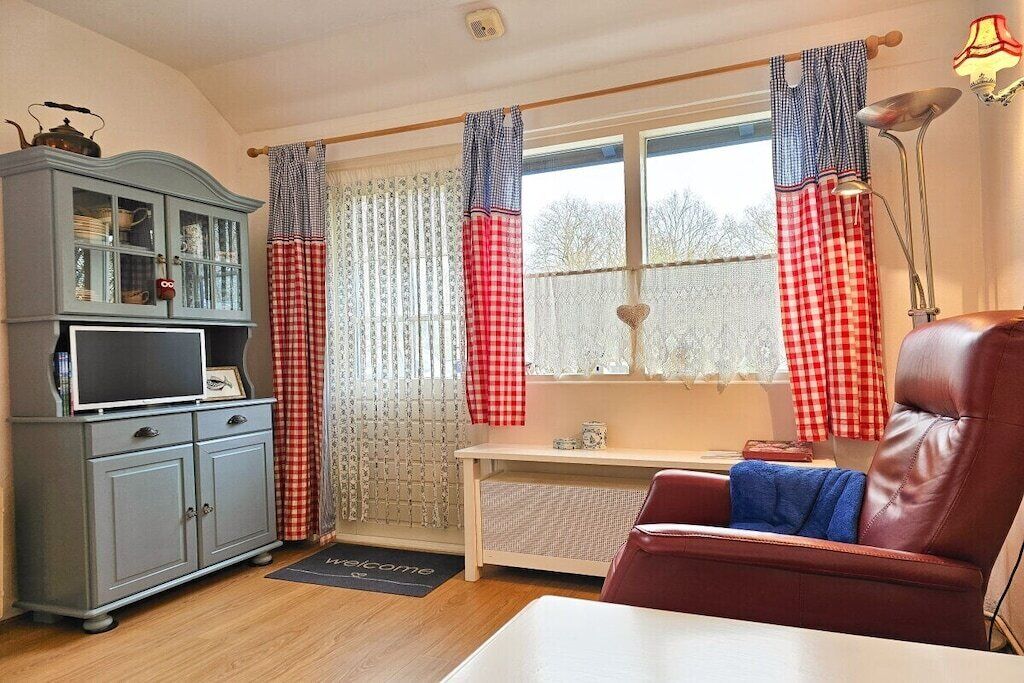 Une pièce comprenant un bureau, un fauteuil en cuir, une armoire et une fenêtre avec des rideaux.