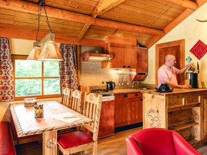 A wooden interior with a kitchen, dining area, and a person at the sink. - Aesthetic Wooden Cottage in Slagharen (Slagharen)