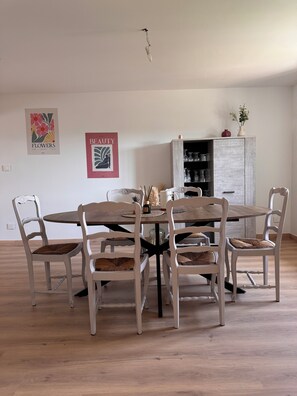 A dining area with a round table and six chairs, a cabinet with glassware, and two framed posters on the wall. - House for 6 people Saint-Nabord (Saint-Nabord)