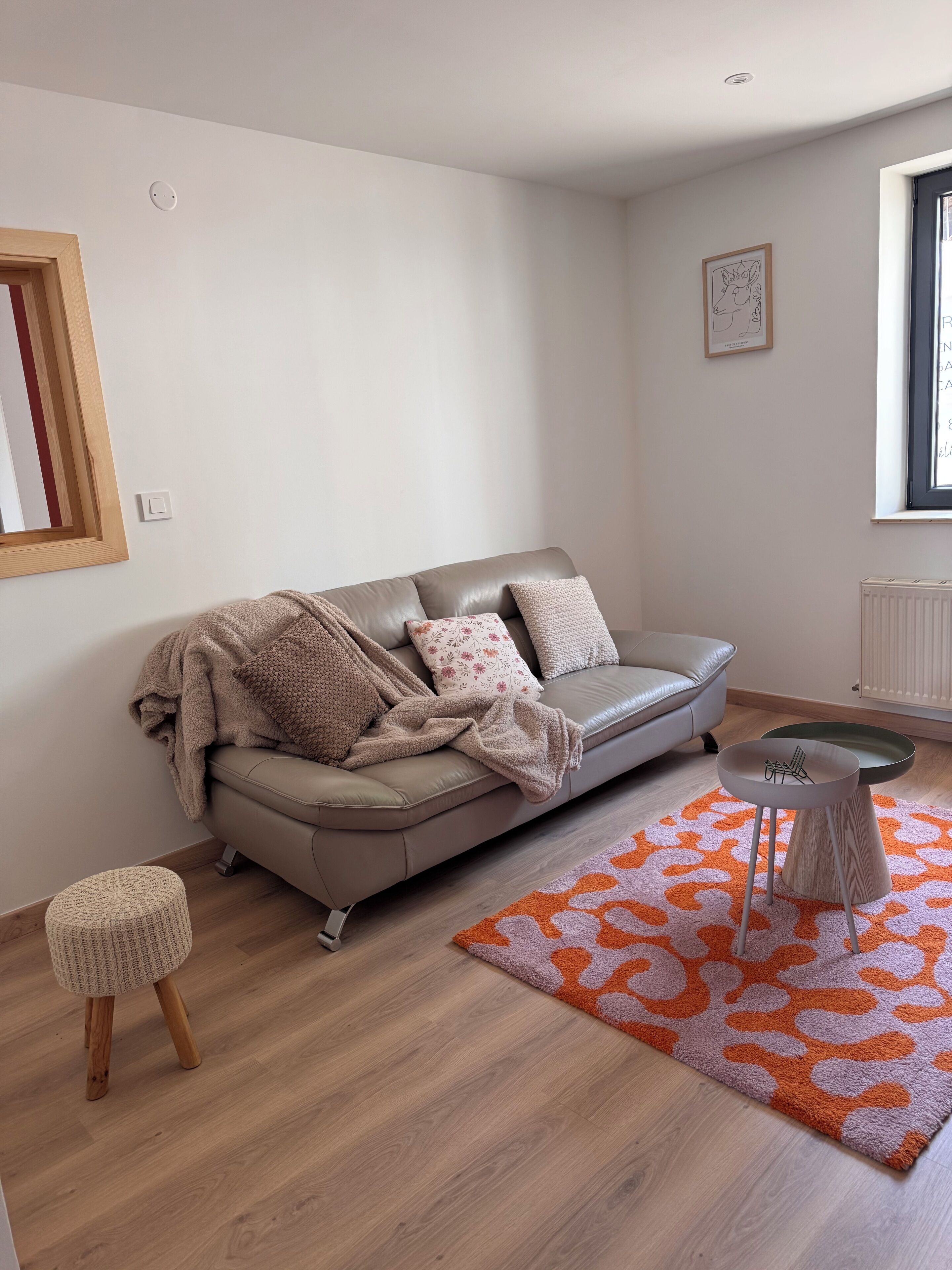 Una sala moderna con un sofá de cuero, una mesita redonda y una alfombra estampada.