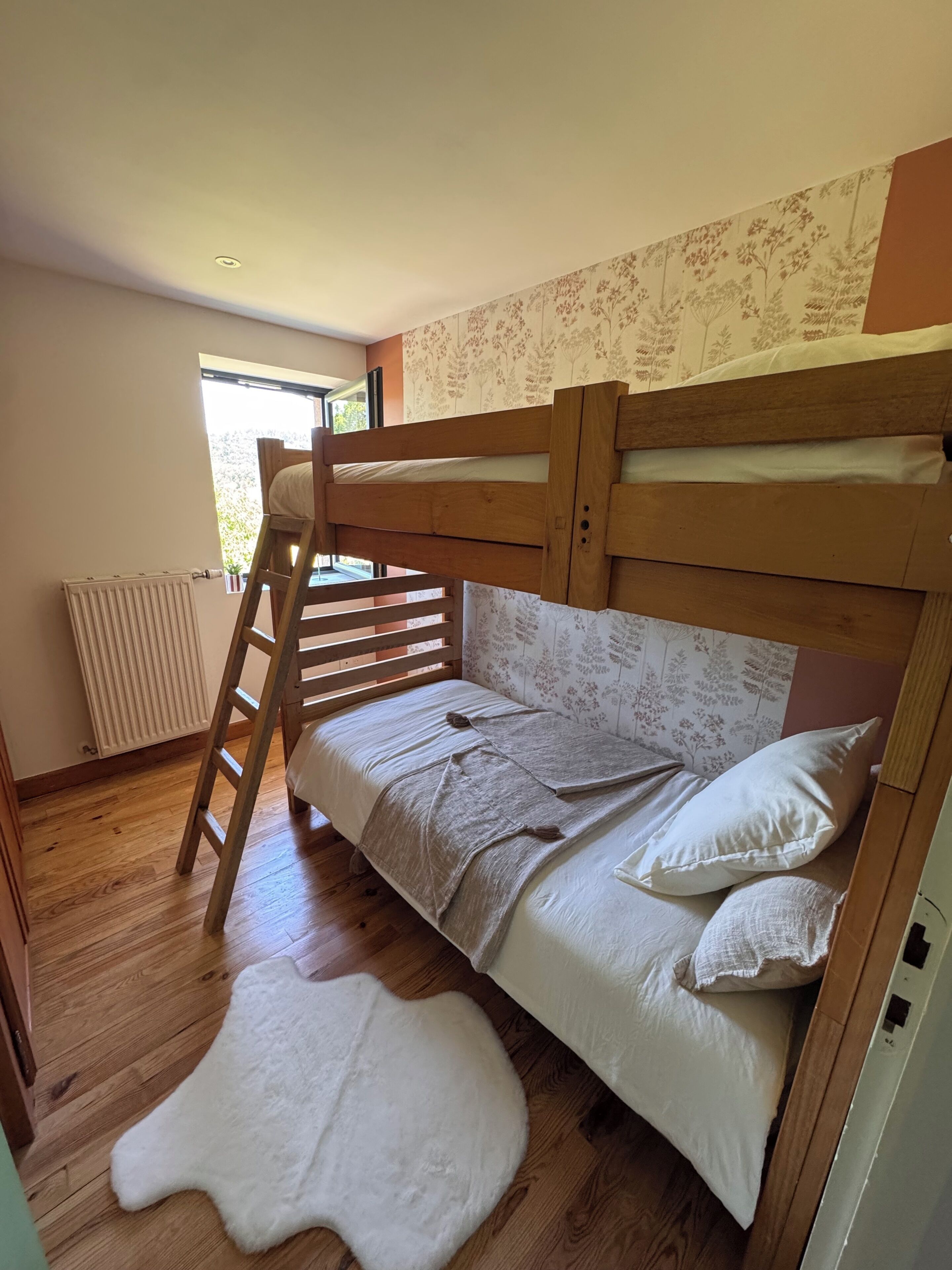 Ein Etagenbett mit einer Stehle, ein flauschiger weißer Teppich und eine Heizung.