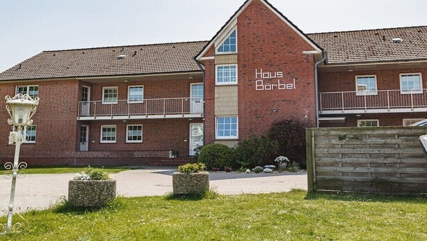 Ein zweistöckiges Backsteingebäude mit der Aufschrift 'Haus Bärbel'.