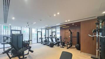 A modern gym with various exercise equipment, large windows, and a clean, well-lit interior.