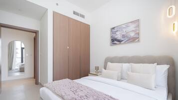 A bedroom with a large bed, a wardrobe, a bedside table, and a painting on the wall.