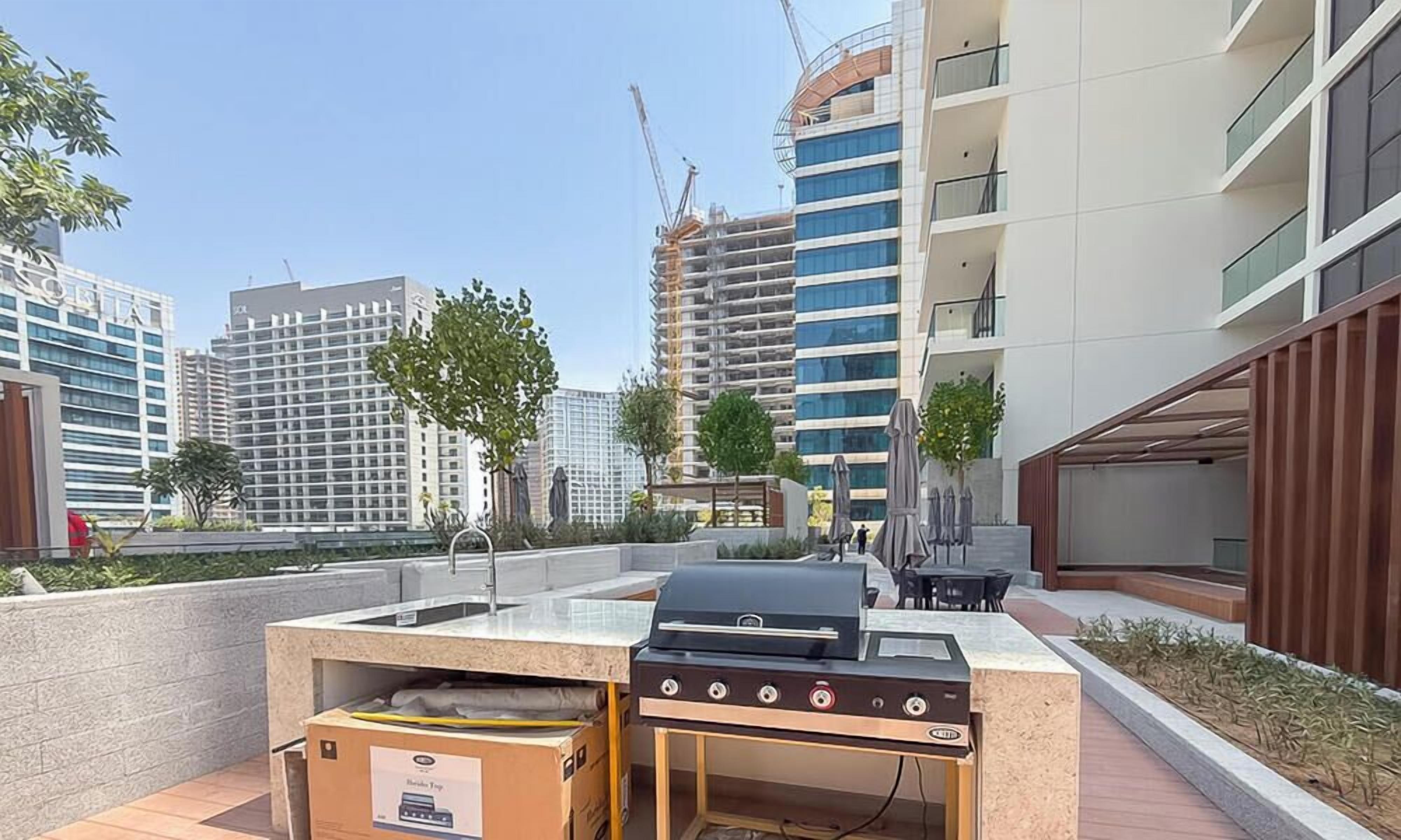 Un espace extérieur aménagé en terrasse, avec un barbecue, une table et des chaises.