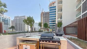 Un espace extérieur aménagé en terrasse, avec un barbecue, une table et des chaises.