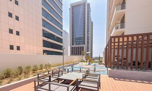 A modern urban setting with high-rise buildings, a central plaza with seating, and a small water feature. - Vogue | VYB at Business Bay close to Downtown (Dubai)