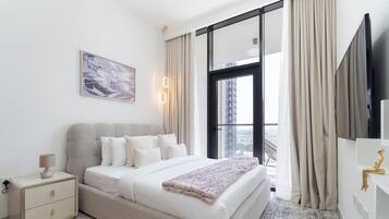 A modern bedroom with a large bed, a nightstand, a lamp, a painting, and a view of the city through a window.