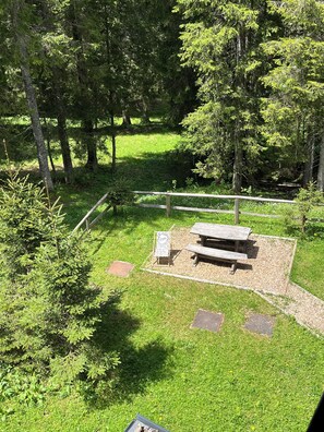 A picnic area with a wooden bench and a sign, surrounded by trees and grass. - Triglav NP Apartment - above Bled (Zgornje Gorje)