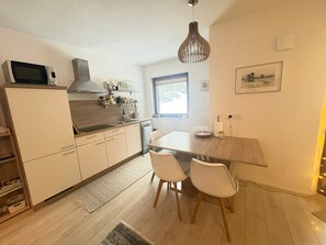 A compact kitchen with a dining area, a microwave on the counter, and a window providing natural light. - Triglav NP Apartment - above Bled (Zgornje Gorje)