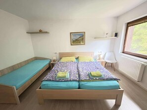 A bedroom with a bed, a bench, a chair, a window, and a picture on the wall. - Triglav NP Apartment - above Bled (Zgornje Gorje)