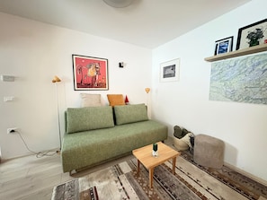 A living room with a green sofa, a wooden coffee table, and a patterned rug. - Triglav NP Apartment - above Bled (Zgornje Gorje)