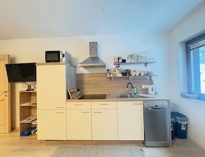 Een moderne keuken met een ingebouwde magnetron, een roestvrijstalen afzuigkap en een vaatwasser.