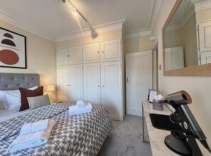 Ein Hotelzimmer mit Bett, Schreibtisch, Fön, Spiegel und Kleiderschrank.