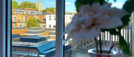 A window with a view of a building with a tower and a flower vase.